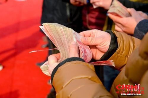 领到钱的农民工正在清点工资。 图片来源:视觉中国