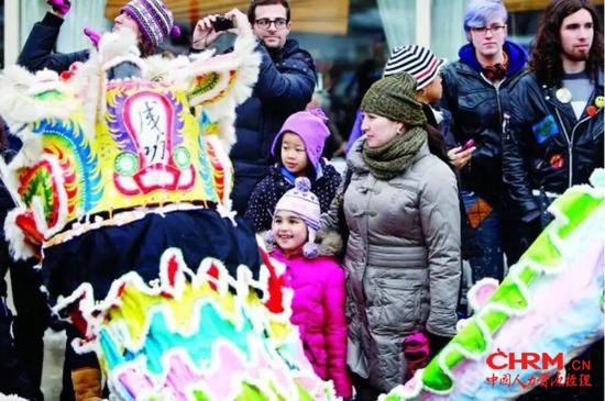  （图：唐人街舞龙吸引外国人驻足观看。）