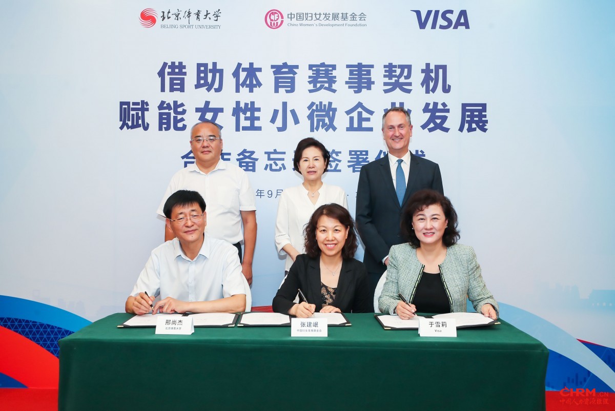 三方领导代表签署合作谅解备忘录。见证领导（二排）从左至右为：北京体育大学产业集团董事长、直属党支部书记张健先生；十二届全国政协常委、十一届全国妇联副主席、书记处书记、中国妇女发展基金会理事长孟晓驷女士；Visa亚太区总裁柯如龙先生 (Chris Clark)。合作谅解备忘录签署领导（一排）从左至右为：北京体育大学党委副书记、工会主席邢尚杰先生；中国妇女发展基金会秘书长张建岷女士；Visa大中华区总裁于雪莉女士。